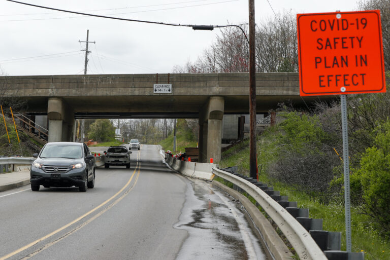 A sign stating "COVID-19 Safety Plan in Effect" marks the approach to the construction zone under an overpass for Interstate 79 as traffic moves through it, in Cranberry Township, Pa., Tuesday, April 28, 2020. (AP Photo/Keith Srakocic)