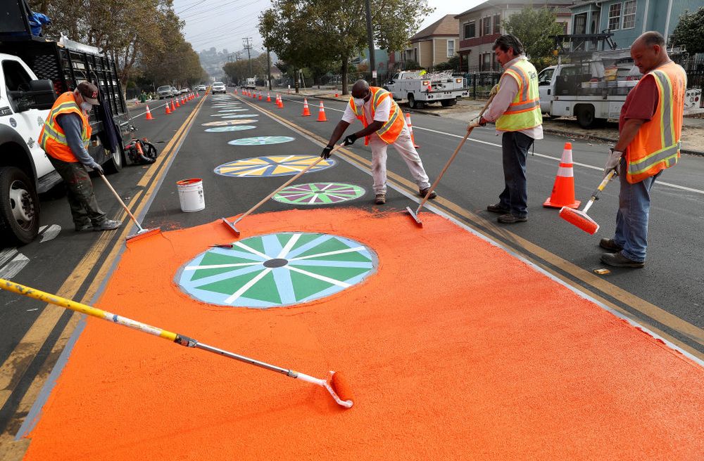 Workers apply orange coating along 90th Avenue in East Oakland, California