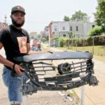 De'Wayne Drummond, president of the Mantua Civic Association, picks up a grill left behind after a crash at 34th Street and Mantua Avenue.