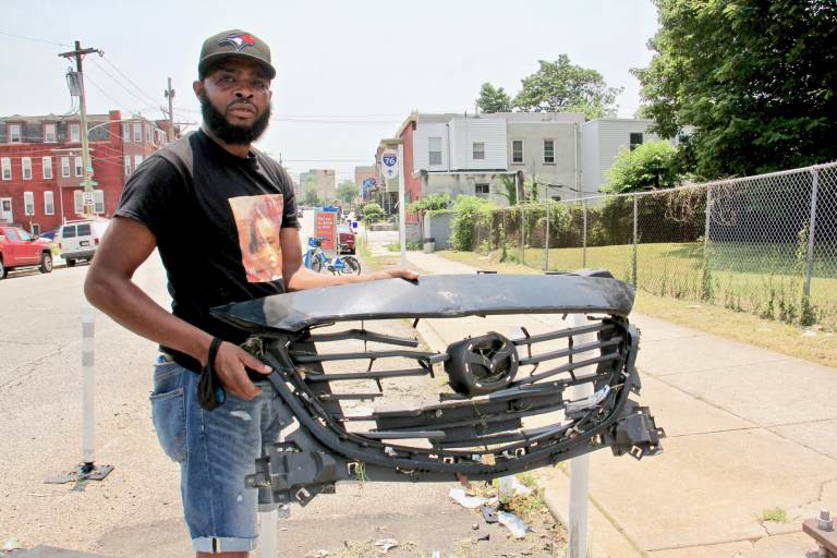 De'Wayne Drummond, president of the Mantua Civic Association, picks up a grill left behind after a crash at 34th Street and Mantua Avenue.