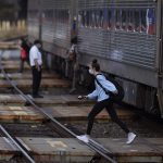 Passengers cross a track after alighting from a SEPTA train in Langhorne, Pa., last October.